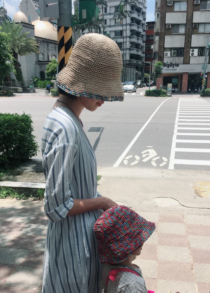 戴著編織帽的成人牽著孩子走在城市街角